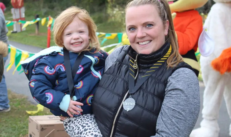 Mother, holding child, mom is wearing Cherrios Challenge medal around her neck
