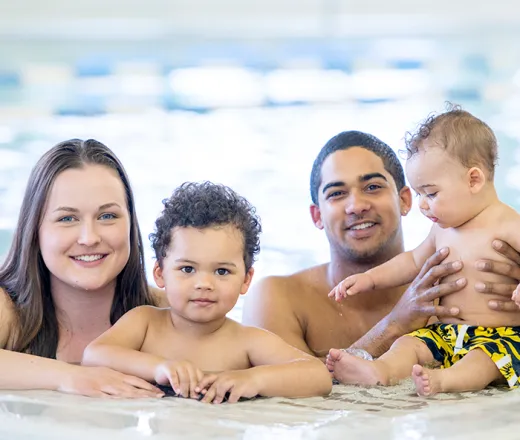 Couple with two young boys swimming in an indoor pool